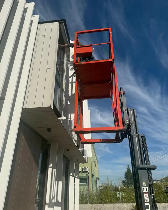 Plataforma elevadora junto a una fachada durante una instalación en altura
