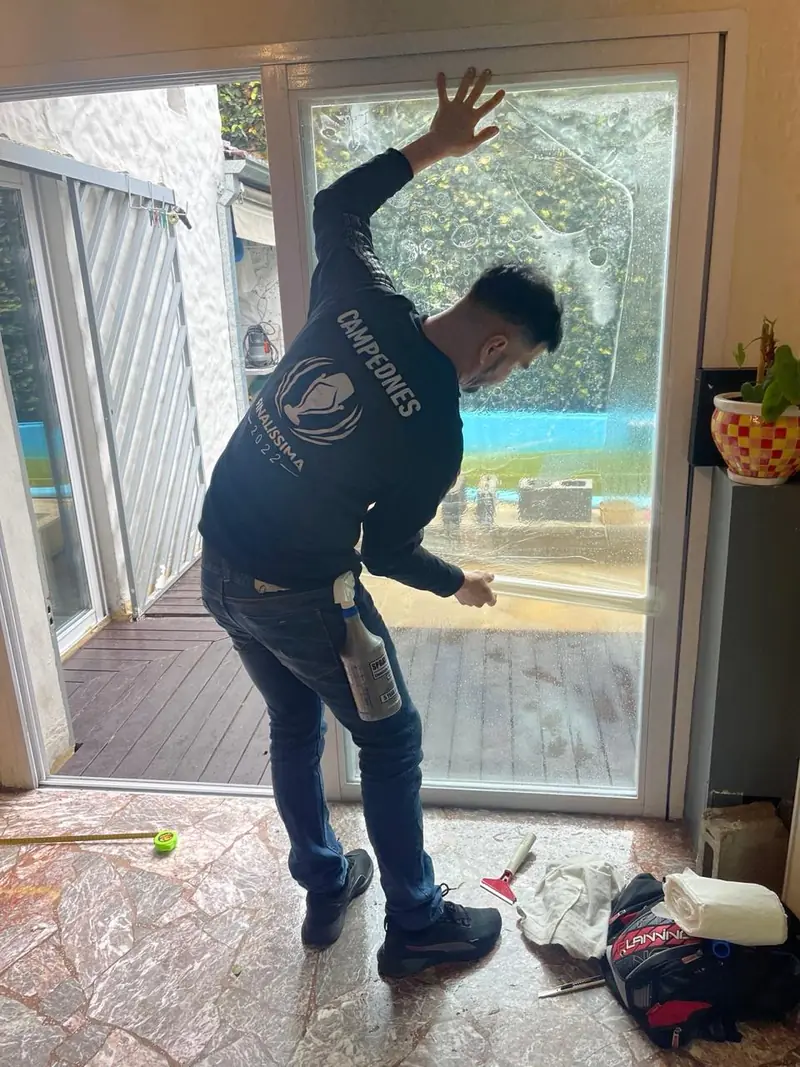 Instalador aplicando lámina en una puerta ventana