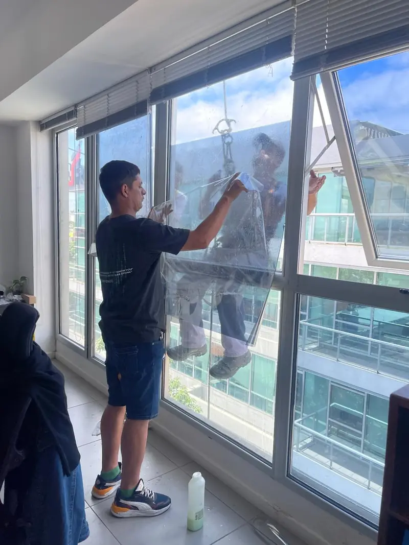 Instalador colocando lámina en un ventanal de departamento